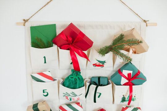 Close-up of part of a Traditional Christmas advent calendar with assorted wrapped gifts hanging on a white wall