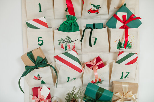 Close-up of part of a Traditional Christmas advent calendar with assorted wrapped gifts hanging on a white wall