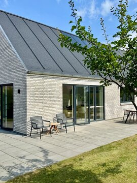 View from the garden of a Modern white brick house with solar panels on a summer day, Samsoe, Jutland, Denmark