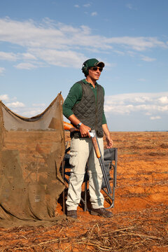 Young man on a bird shoot standing in a field holding a shotgun, South Africa