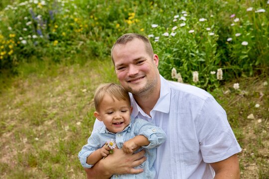 Portrait of a smiling man sitting in a meadow with his son on a summer day, Albion Meadows, Alta, Utah, USA