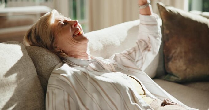 Laughing, home and senior woman with phone in lounge, thinking or funny message on social media app. Happy, online and mature person with mobile in living room, reflection and reading post in house