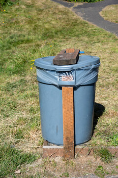 DIY, do it yourself, animal and wind proofed garbage cans, plastic trash bins reinforced with wood boards outdoors in a public park
