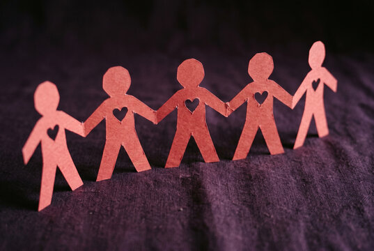Red paper cutout figures holding hands with heart shapes