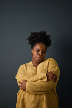 Portrait of young adult African American woman smiling with arms crossed, representing self love and mental wellbeing, ideal for healthcare and lifestyle campaigns, vertical
