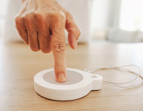 Close-up of an older persons finger pressing the large round button of a plain call pendant with a neck cord