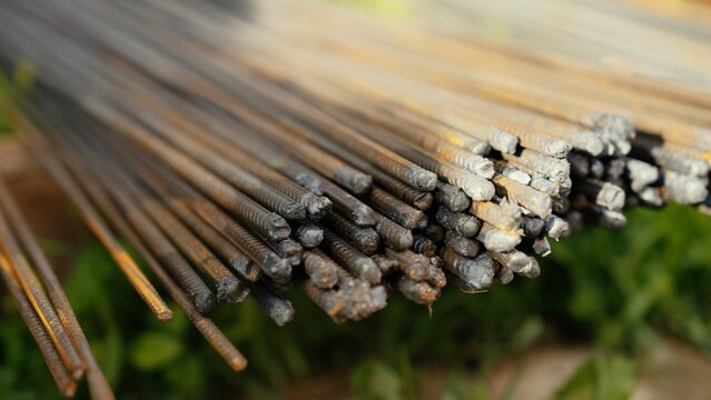 Steel reinforcing bars, also known as rebar, bundled together on a construction site, showing their textured surface and slight rust, ready for concrete reinforcement