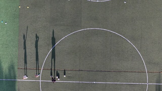 Aerial view of a football pitch with long shadows of players and field markings on the green turf in Lisbon, Lisbon, Portugal.