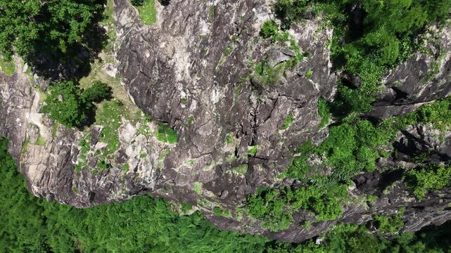 Majestic granite stone cliff and lush green forest in Nakhon Nayok province, Thailand.