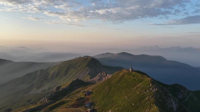 Aerial view of Cerreto Laghi mountain landscape with rolling green hills, rocky ridges, and misty valleys under a soft morning sky in Cerreto Laghi, Emilia-Romagna, Italy.