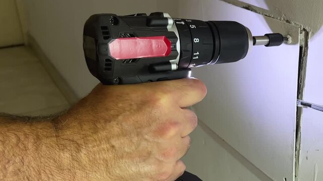 Close-up view of a skilled handyman's hands using a professional cordless power screwdriver