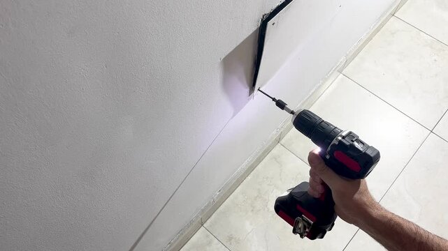 Skilled worker's hand holding a cordless electric screwdriver during home improvement, construction or renovation projects