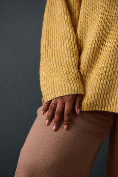 Vertical image of young adult African American woman hand resting on leg, showcasing jewelry ring. Close up shot ideal for fashion retail, lifestyle marketing and manicure promotion