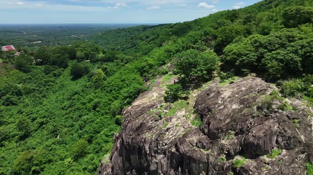 Majestic granite stone cliff and lush green forest in Nakhon Nayok province, Thailand.
