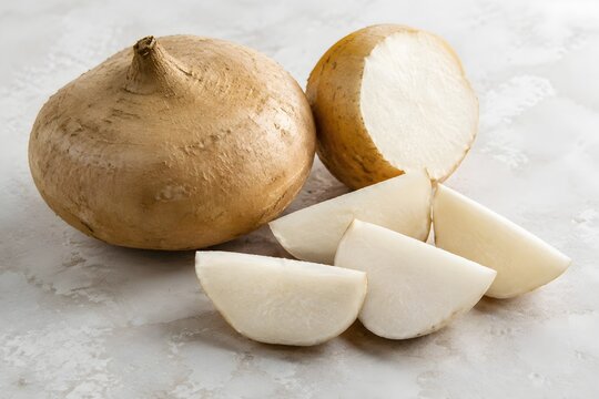 Fresh Jicama Displayed Whole and Cut into Crisp White Wedges on a Pale Stone Background