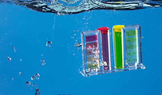 PH acid level test kit on quality water on screen. PH acid level tester kit tools fall under water splashing splattering with air bubble over blue background isolated