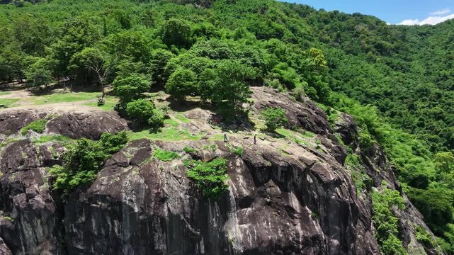 Majestic granite stone cliff and lush green forest in Nakhon Nayok province, Thailand.