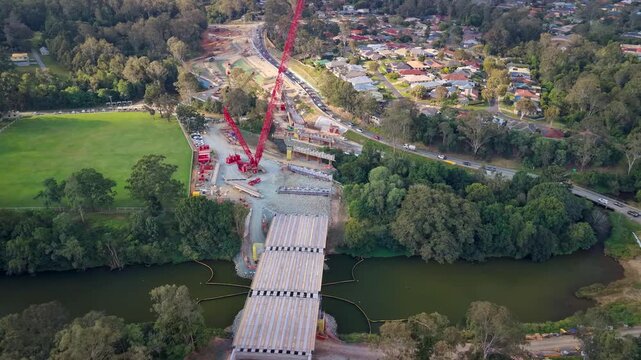 Aerial view of Youngs Crossing Road bridge construction with heavy machinery and traffic in Bray Park, Queensland, Australia.