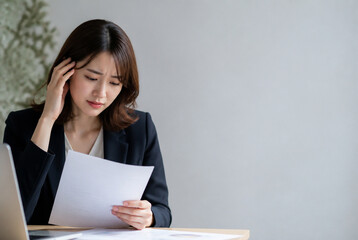 Fototapeta premium 書類を見て頭を抱え悩む若い日本人女性ビジネスウーマン Generative AI