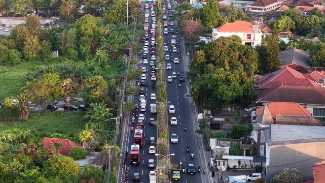 Aerial view of heavy traffic congestion at the Simpang Sanur - Simpang Tohpati intersection with cars and motorcycles in Denpasar Selatan, Bali, Indonesia.
