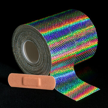 A roll of holographic rainbow tape is shown next to a single adhesive bandage on a black background.