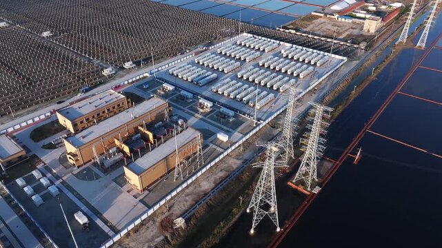 Aerial view of a large-scale energy storage station adjacent to photovoltaic arrays and coastal salt pans