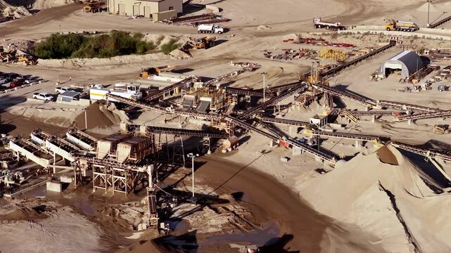 Aerial view of industrial aggregate operations and gravel pit with heavy machinery, conveyor belts, and piles of sand and gravel in Bluffdale, Utah, United States.