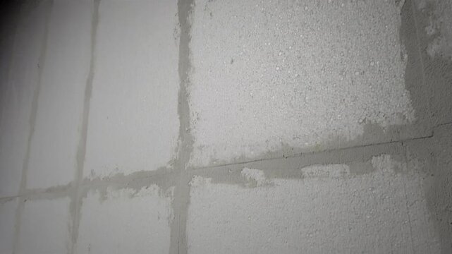Exploring wall construction techniques at a site in winter during evening hours focusing on surface details and material texture for improvement insights