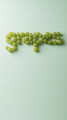 Obraz premium Green grapes arranged into word grapes spelling on pale green backdrop. Minimalist fruit art photography for creative design projects and food blogs.
