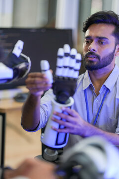 Young engineers discuss robotic technology while working together with a robotic arm in a blue-lit innovation lab.