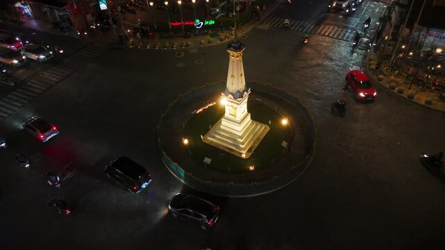 Aerial view of Tugu Yogyakarta Monument illuminated at night with surrounding traffic and city lights in Kecamatan Jetis, Daerah Istimewa Yogya, Indonesia.