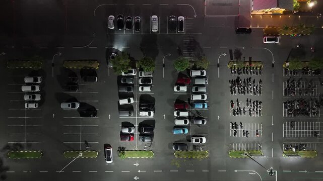 Aerial view of Parkir Lotte Mart at night with rows of parked cars and motorcycles in Kecamatan Denpasar Selatan, Bali, Indonesia.