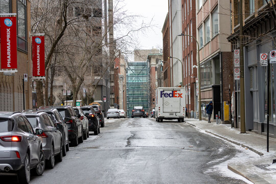 MONTREAL, CANADA, 22 December 2025 : Urban street scene, delivery van, parked cars, winter cityscape, modern architecture