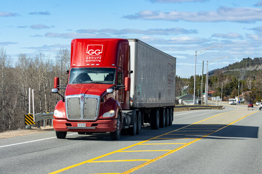 Quebec, Canada, 24 April 2026 : A red Groupe Goyette semi-truck drives on a highway under a blue sky with clouds.