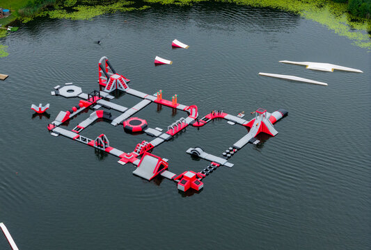 Aerial view of an inflatable water park with slides, trampolines, and floating obstacles on a calm lake in Vilnius, Vilniaus apskritis, Lithuania.