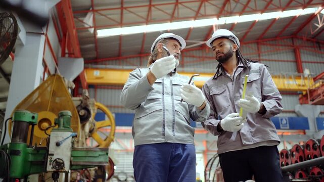 Two quality control engineers inspecting metal part in factory