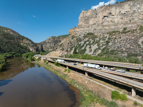 Aerial view of Glenwood Canyon showing Interstate 70 highway construction and the Colorado River next to the highway and vehicles in the rugged landscape in Glenwood Springs, Colorado, United States.