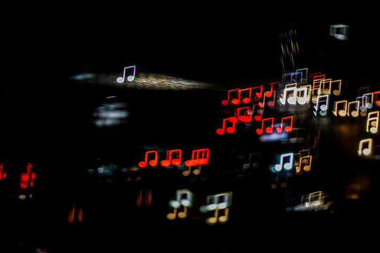 Abstract musical note shaped bokeh lights with motion light streak on black background. Creative backdrop for music event, concert, podcast banner, and sound design.