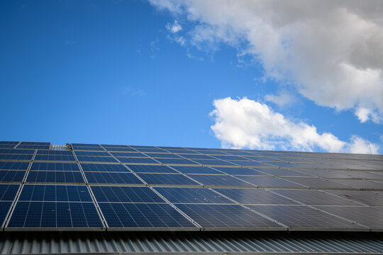 Solar panels on a roof harnessing renewable energy under a clear blue sky with clouds - horizontal