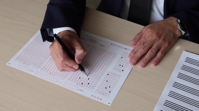マークシート方式の解答用紙にペンで回答を記入する手元