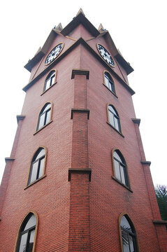A tall red brick clock tower with two clocks on top
