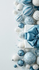 Obraz premium Vertical flat lay of blue and white Christmas ornaments and a gift box with a large blue bow.