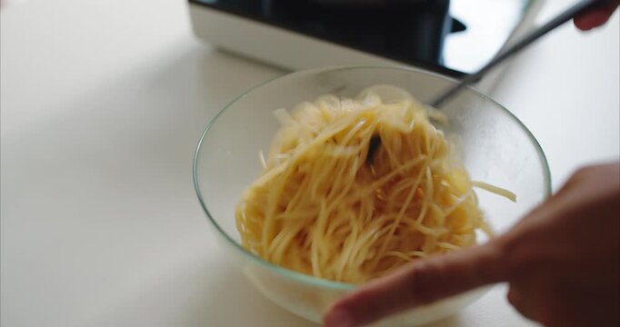 Close up of Asian Woman Hands Tossing Spaghetti Pasta in Bowl on Table,  Faceless Female Mixing Noodle Food Ingredient to Prevent Sticking in Kitchen Room, Home Cooking Concept.