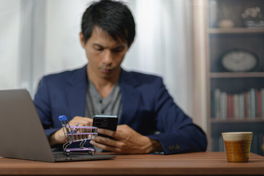Young man shopping online with credit card at home workspace with laptop and shelves
