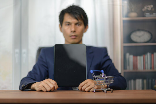 Businessman Holding Digital Tablet and Small Shopping Cart in Office Setting