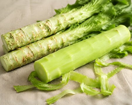 Fresh Celtuce Stems Displayed Whole and Peeled Showing Crisp Pale Green Interiors on Linen Display