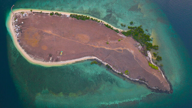 Aerial view of Pulau Kenawa surrounded by turquoise waters and coral reefs in Poto Tano, West Nusa Tenggara, Indonesia.