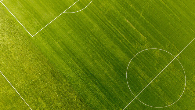 Aerial view of a vibrant green soccer field with white pitch markings and a center circle in Gdansk, Poland.