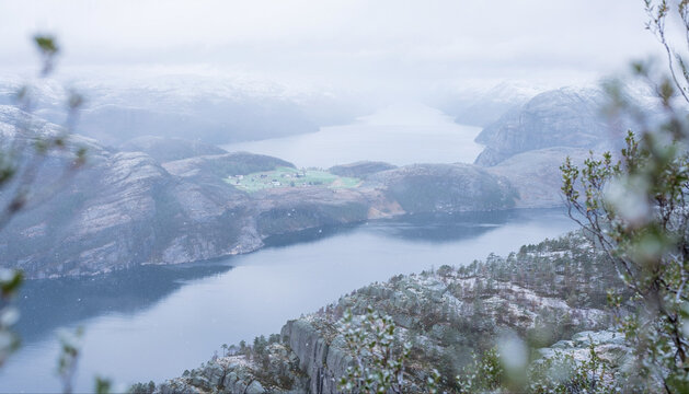 title": "Serene Norwegian Fjord Landscape with Snow-Capped Mountains, Calm Waters, and a Small Village in the Distance, Capturing the Tranquil Beauty of the Norwegian Wilderness", "description": "Thi