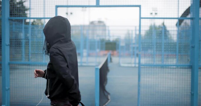Woman enjoying freedom while dancing alone in a rainy outdoor tennis court